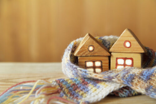 Dwa drewniane figurki domków w szaliku